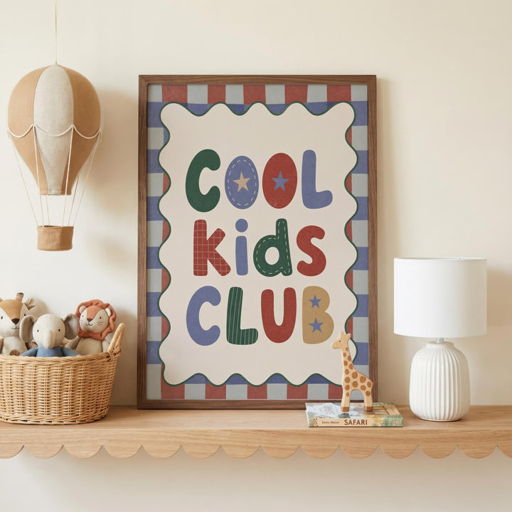 a framed poster with the text "Cool Kids Club" on it, placed on a shelf next to a basket of stuffed animals and a white lamp.