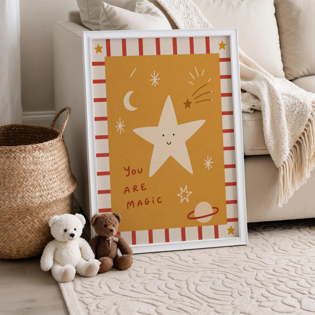 A framed poster with a star and a message is displayed on a wall, accompanied by two stuffed teddy bears sitting on the floor next to a woven basket.