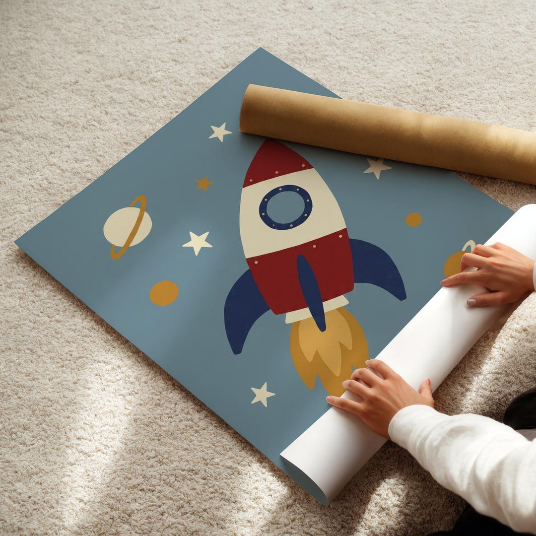 A child's hands are holding a roll of paper, which appears to be a large piece of paper with a rocket ship design printed on it.