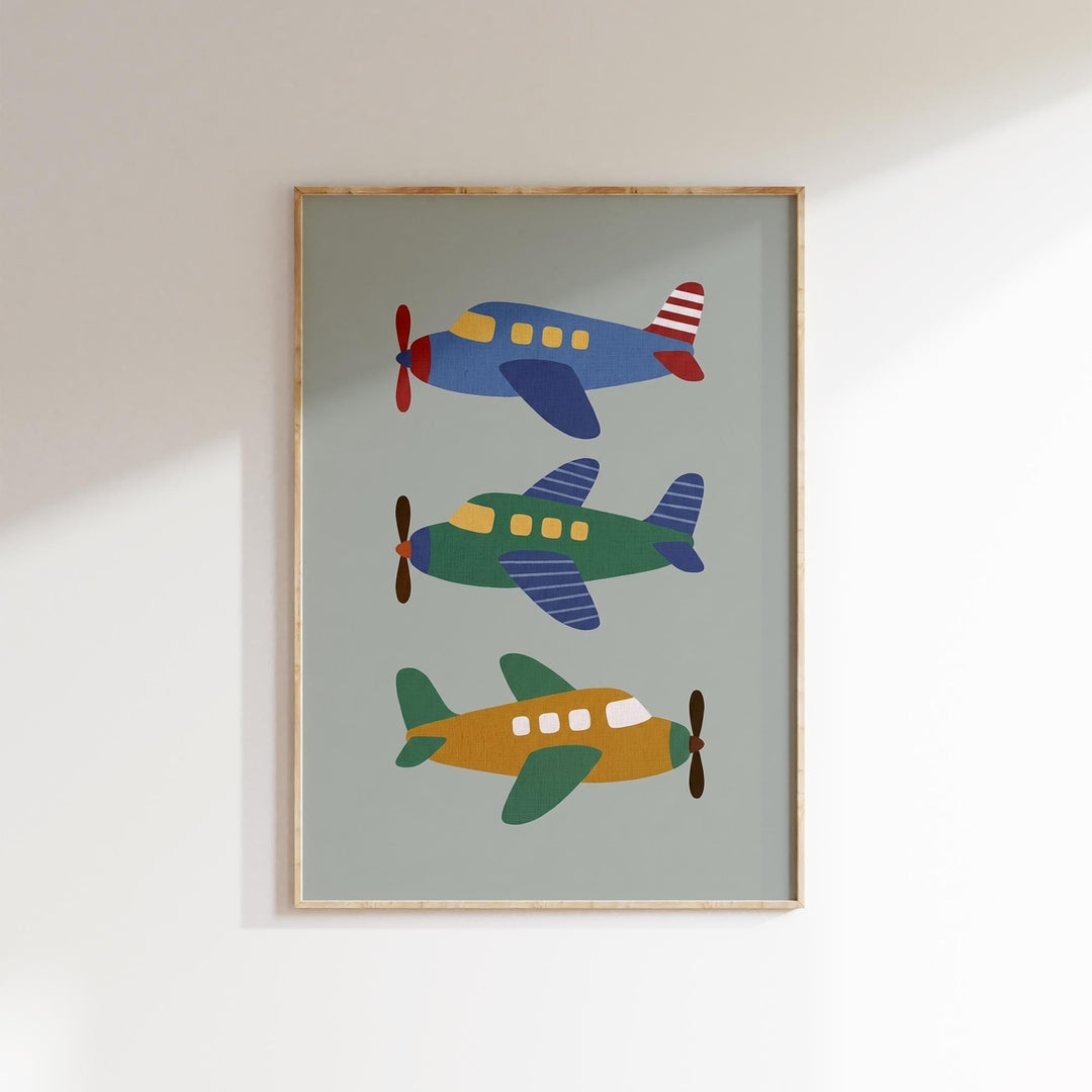 A framed print of three colorful airplanes on a light green background.
