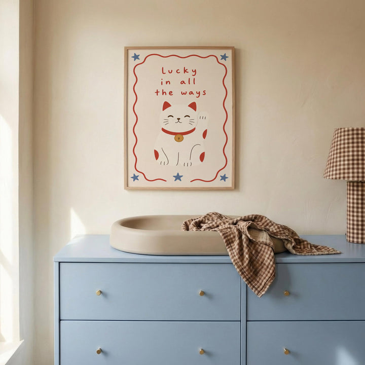 a blue dresser with a white sink on top, and a framed poster with a cat and the text "Lucky in all the ways" hanging on the wall above the dresser.