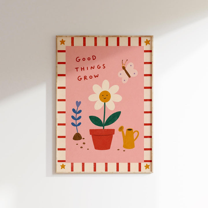 The image is a framed poster with a pink background, featuring a white flower, a watering can, and a butterfly. The text "GOOD THINGS GROW" is written above the flower, and there is a small star on the bottom left corner of the poster.