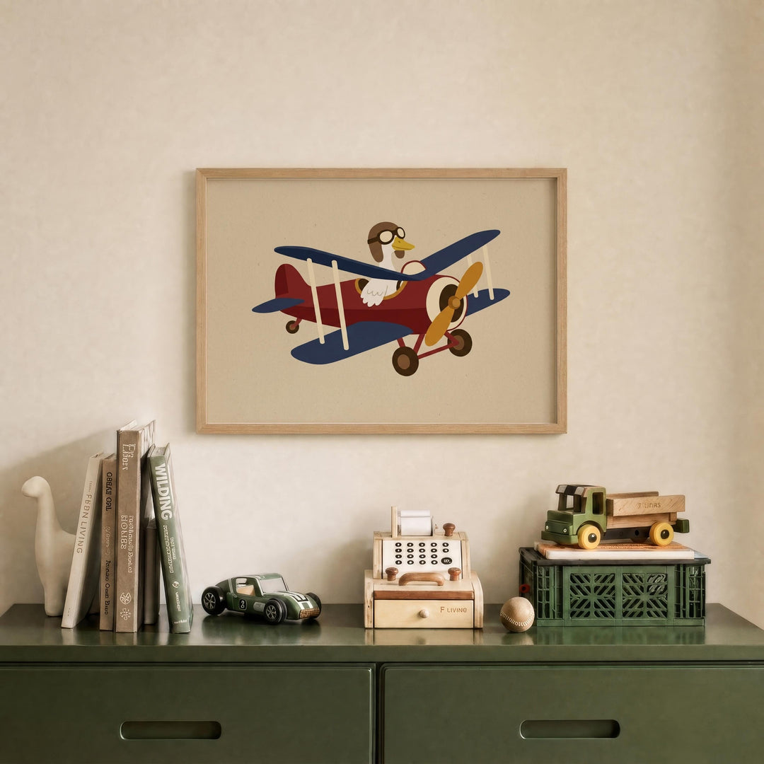 a framed illustration of a red and blue biplane with a cartoon character on it, hanging on a wall above a green dresser with various toys and books on it.