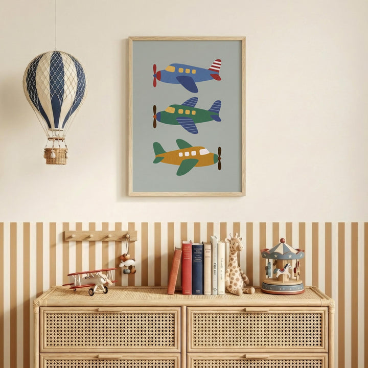 a wooden dresser with a framed picture of three colorful airplanes hanging above it, along with a hot air balloon and a carousel. The dresser also has a collection of books and toys on top.