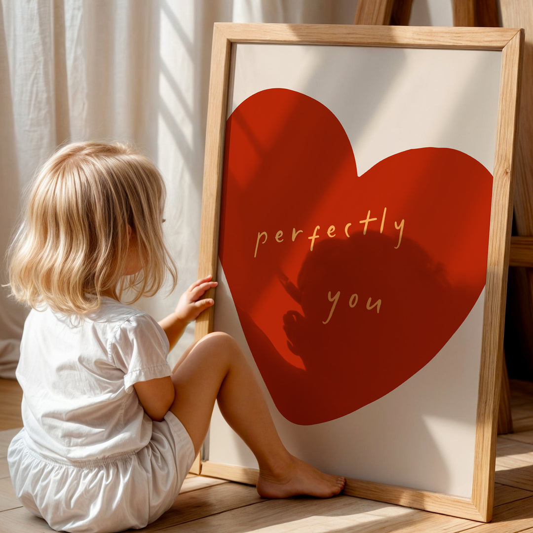 a little girl sitting on the floor next to a heart