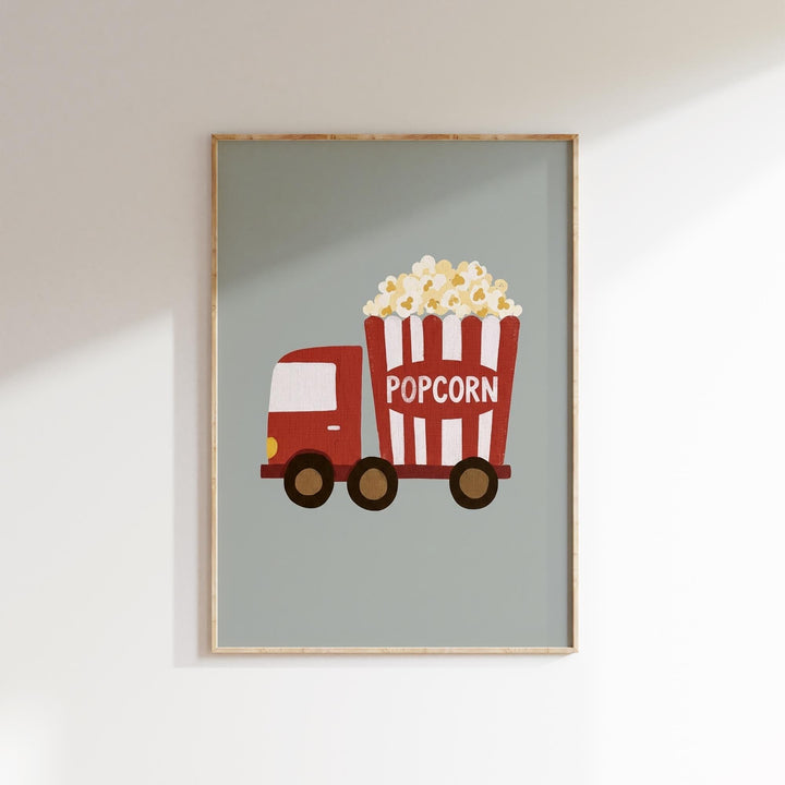 A framed illustration of a red and white striped truck with a large bucket of popcorn on the back.