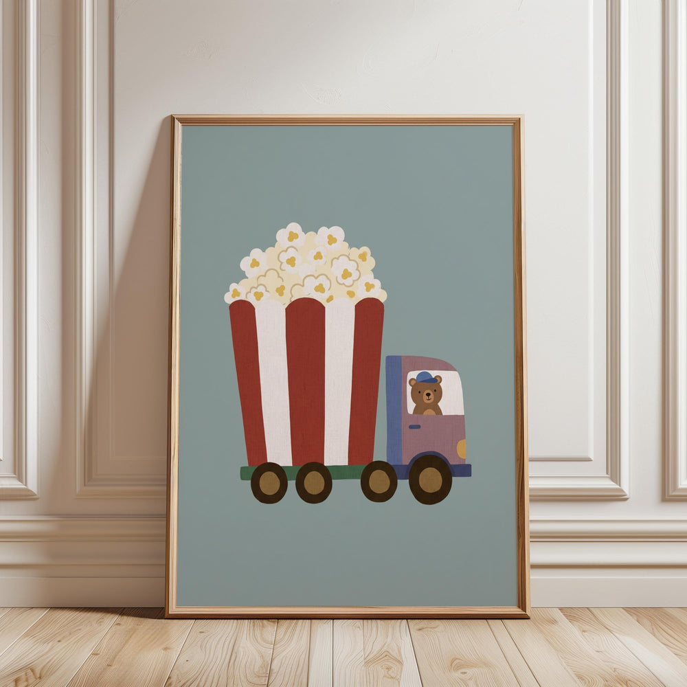 A framed illustration of a red and white striped truck carrying a large bucket of popcorn, with a teddy bear inside the truck.