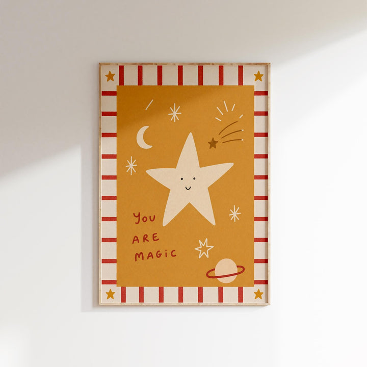 The image is a framed artwork featuring a star with a face, surrounded by celestial elements such as a crescent moon, stars, and a planet. The text "You are magical" is written below the star.