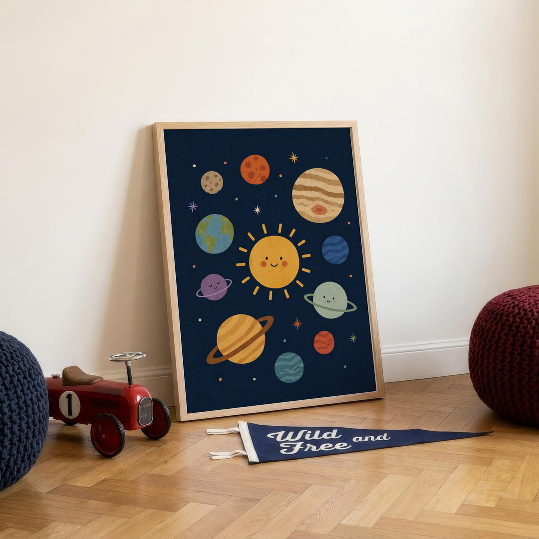 a framed poster of a solar system with planets and a smiling sun, placed on a wooden floor next to a toy car and a red bean bag chair.