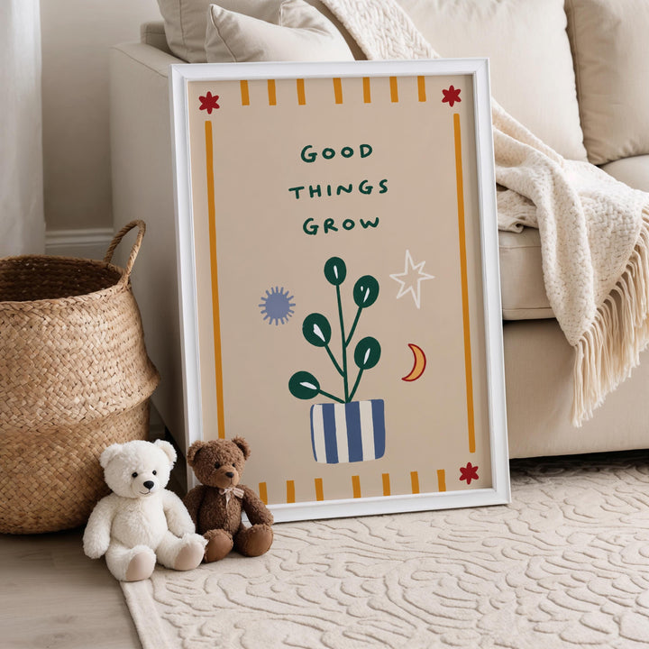 A framed poster with the text "Good things grow" is displayed on a wall, accompanied by a small teddy bear and a woven basket.