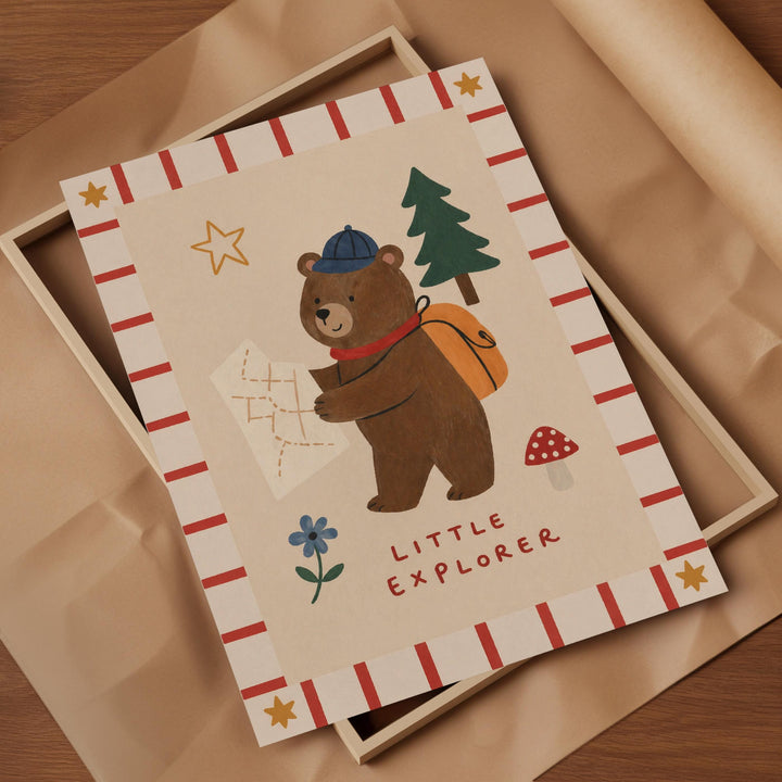 a bear holding a map and a backpack, with the text "Little Explorer" written below the bear.