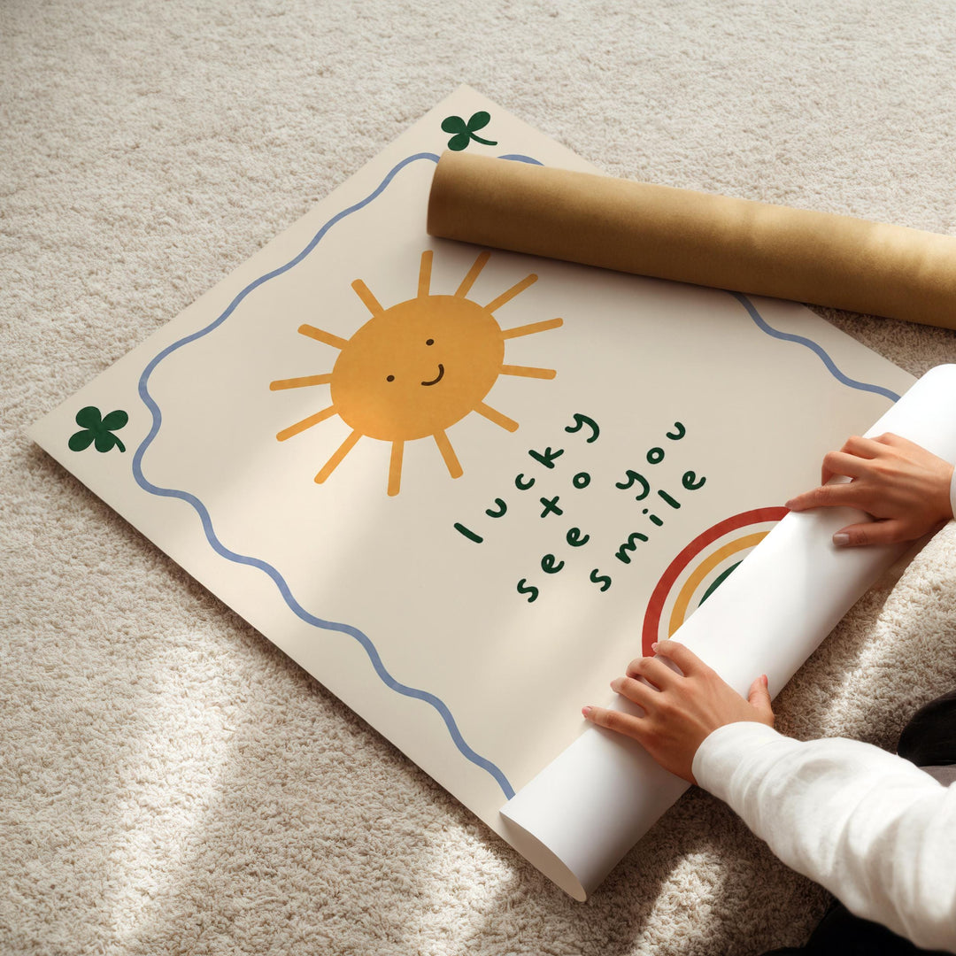 A child's hands are seen rolling up a poster with a sun and rainbow design, along with the text "lucky see you smile".