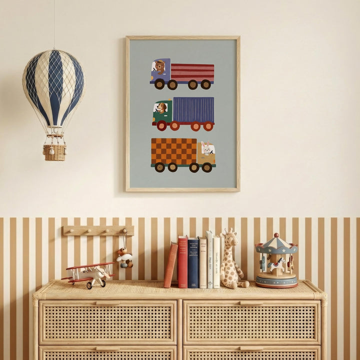 a wooden dresser with a framed poster of colorful toy trucks hanging above it, along with a hot air balloon and a carousel figurine on the dresser.