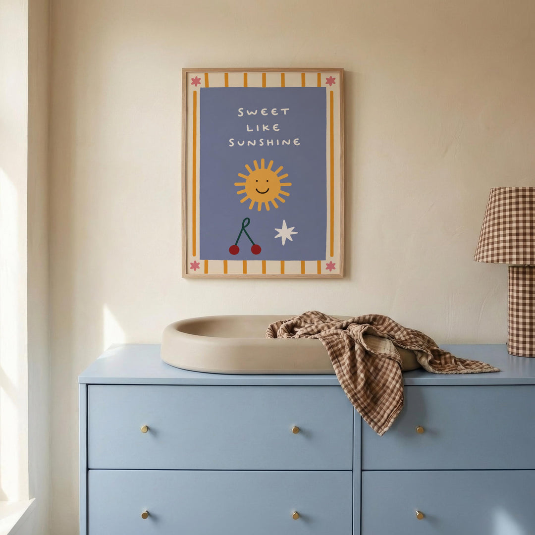 a blue dresser with a white sink on top, and a framed poster with a cheerful design hanging on the wall above the dresser.