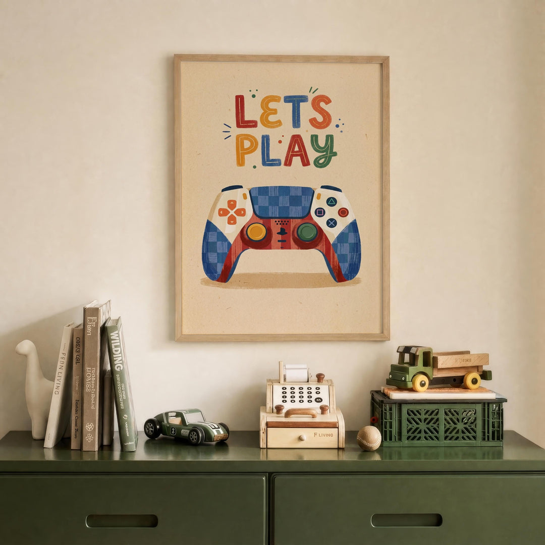 a framed poster with the text "LET'S PLAY" above a colorful illustration of a video game controller, which is displayed on a wall above a green dresser. The dresser has various items on it, including a toy car, a toy truck, and a small toy cash register.