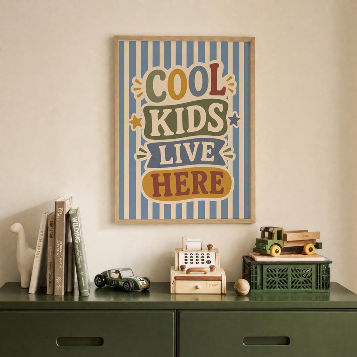 a framed poster with the text "COOL KIDS LIVE HERE" hanging on a wall above a green dresser with various items on it, including books, toys, and a toy cash register.