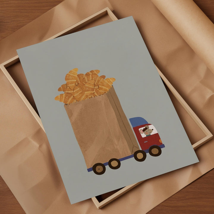 A framed illustration depicting a paper bag filled with golden-brown croissants, with a red and blue truck carrying the bag.
