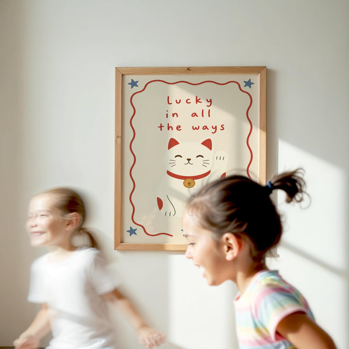 Two young girls are running in front of a framed poster with a cat and the text "Lucky in all the ways".