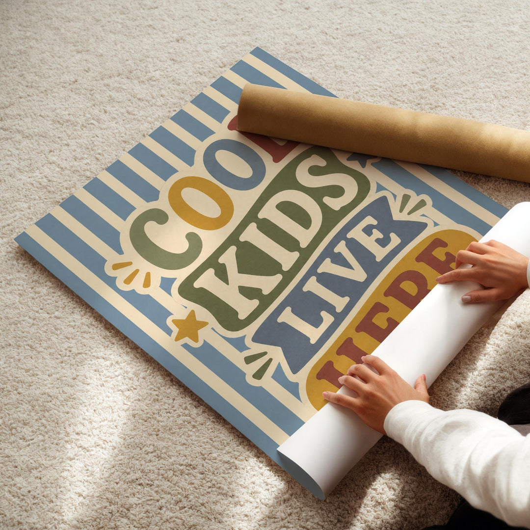 A person's hands are rolling up a poster with the text "COOL KIDS LIVE HERE" on it.