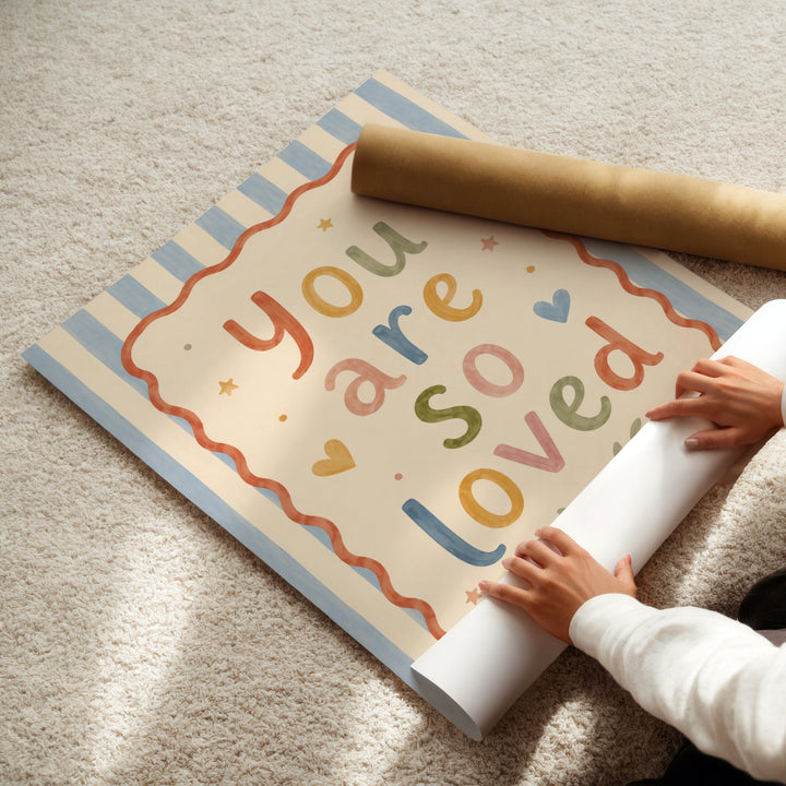 Illustrated nursery print reading 'you are so loved' in colourful folk lettering with hearts and stars