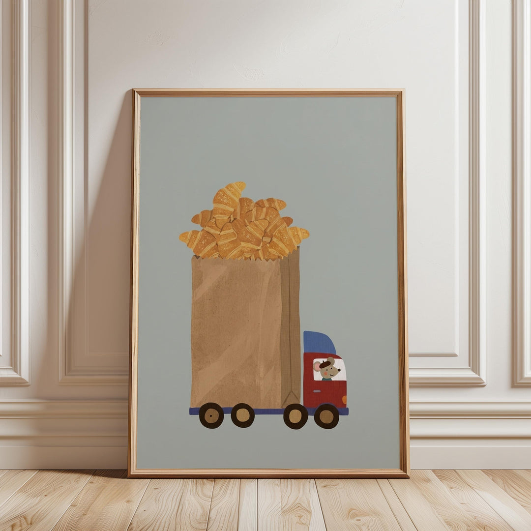 A framed illustration depicting a truck carrying a large bag filled with golden-brown pastries, likely croissants, against a light blue background.