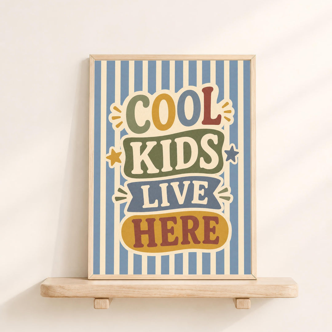 a framed poster with the text "COOL KIDS LIVE HERE" on it, displayed on a wooden shelf against a white wall.