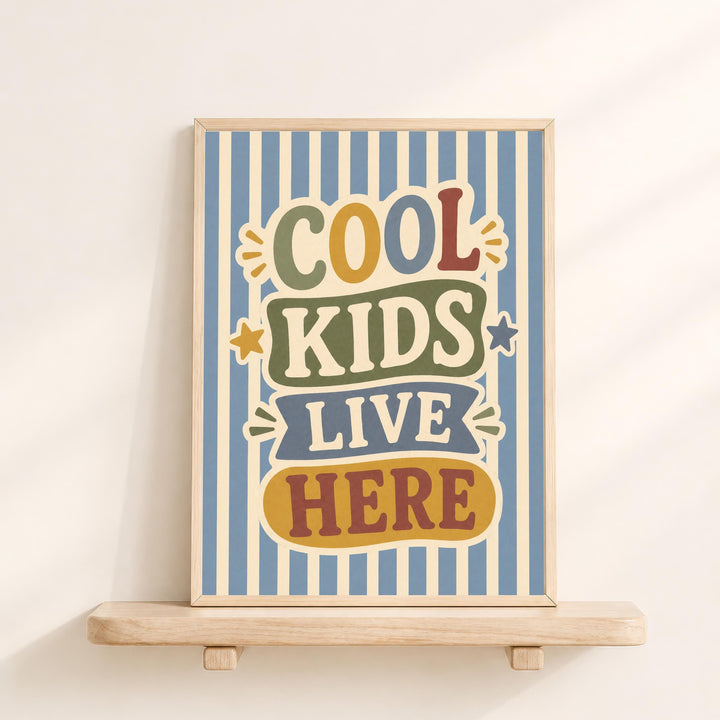 a framed poster with the text "COOL KIDS LIVE HERE" on it, displayed on a wooden shelf against a white wall.
