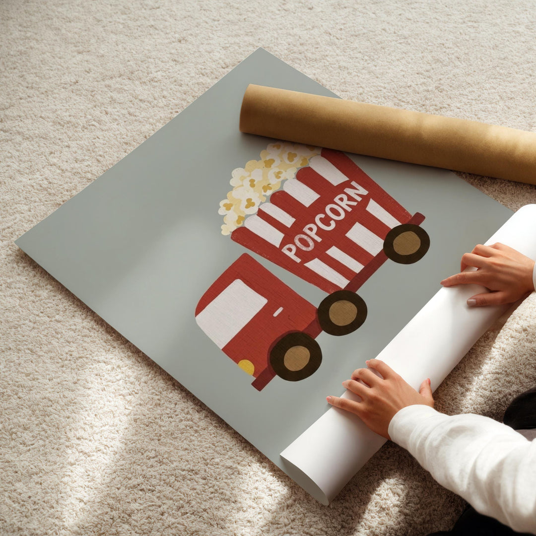 A person's hands are holding a roll of paper, which appears to be a poster or artwork depicting a red and white popcorn truck.