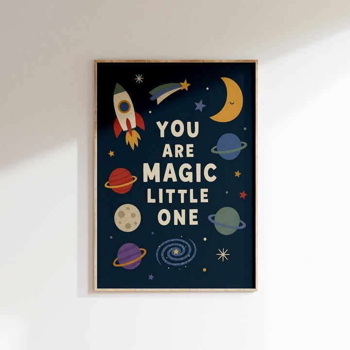 The image is a framed poster with a space-themed design, featuring a rocket ship, planets, and stars. The text on the poster reads "YOU ARE MAGIC LITTLE ONE".