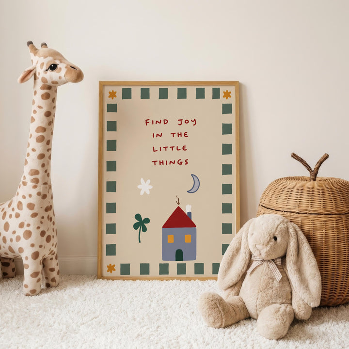 a giraffe and a stuffed rabbit, both placed on a white carpeted floor. In the background, there is a framed poster with a message about finding joy in the little things.