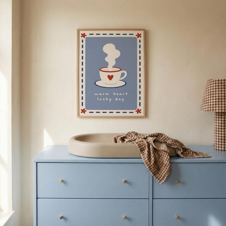 a blue dresser with a white sink, a framed poster of a cup with steam, and a plaid blanket on top.