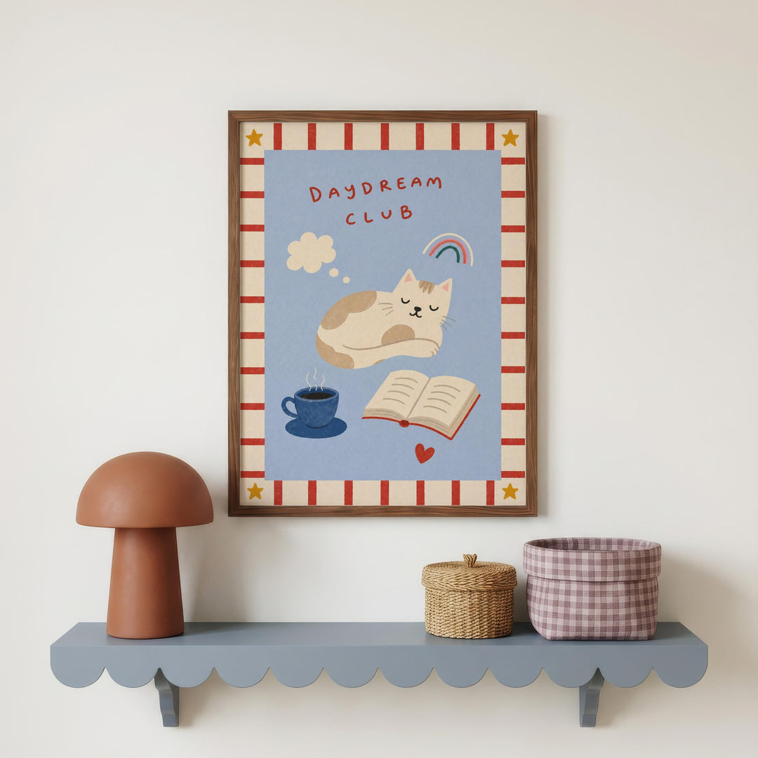 a framed poster of a cat sleeping on a blue background, with a mushroom-shaped lamp and a woven basket below it.