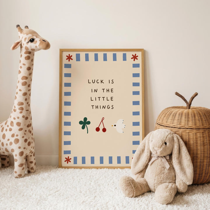 a giraffe and a stuffed rabbit, both placed next to a framed sign with the text "LUCK IS IN THE LITTLE THINGS".
