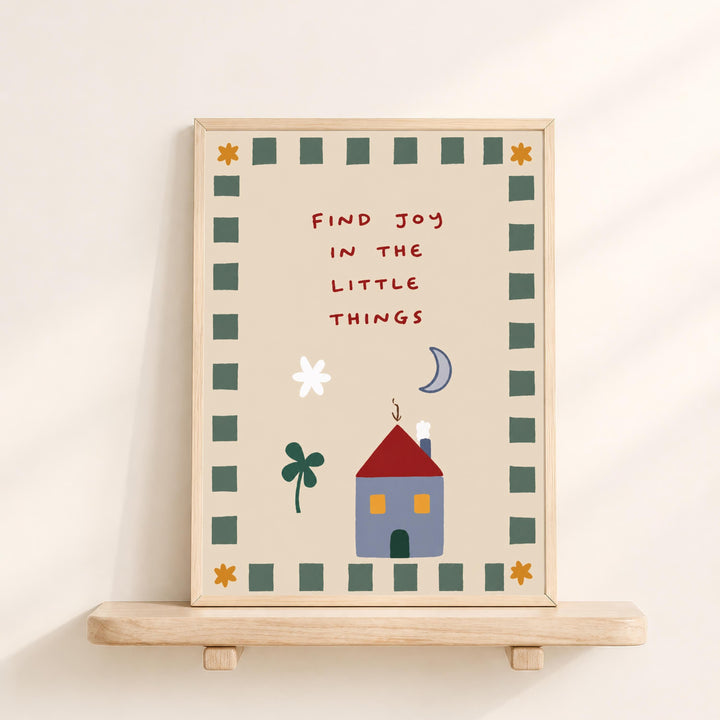 The image is a framed poster with a whimsical illustration of a house, flowers, and a moon, along with the text "Find joy in the little things" written in a playful font.