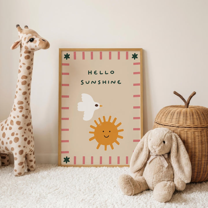 A giraffe toy and a stuffed rabbit toy are placed next to a framed poster with a sun and bird design, and a wicker basket.