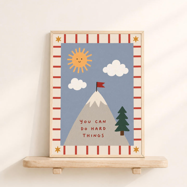 The image is a framed illustration depicting a mountain with a flag on top, surrounded by clouds and a sun. The text "You can do hard things" is written below the mountain.