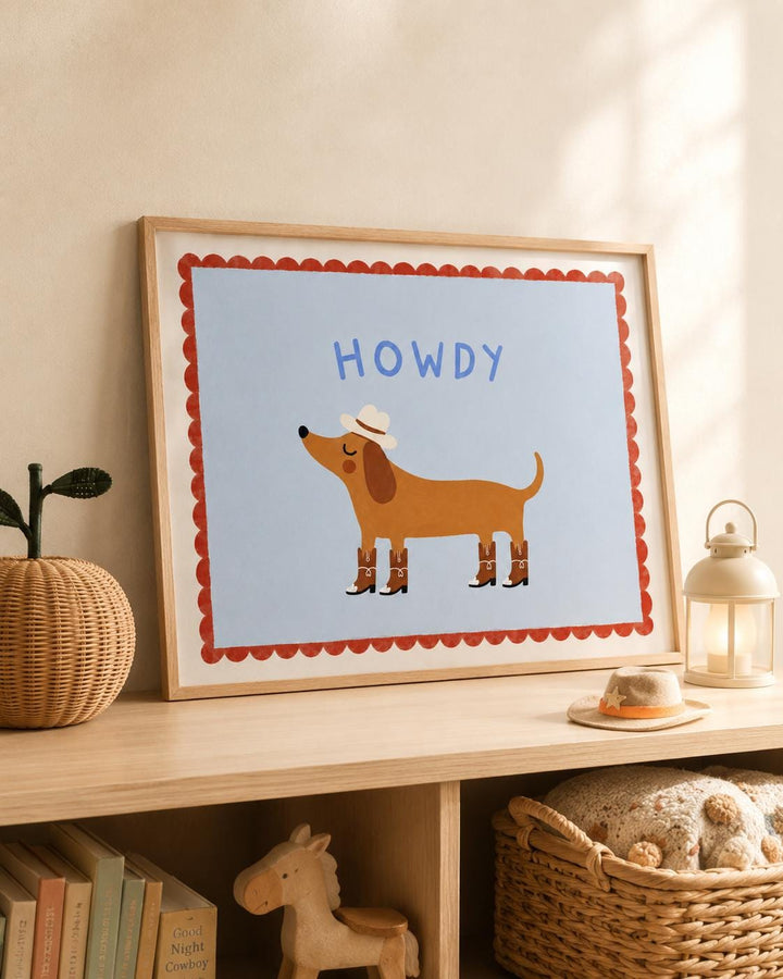 a framed illustration of a dog wearing a cowboy hat and boots, with the word "HOWDY" written above it. The dog is standing on a wooden shelf, and there are some books and a small toy horse nearby.