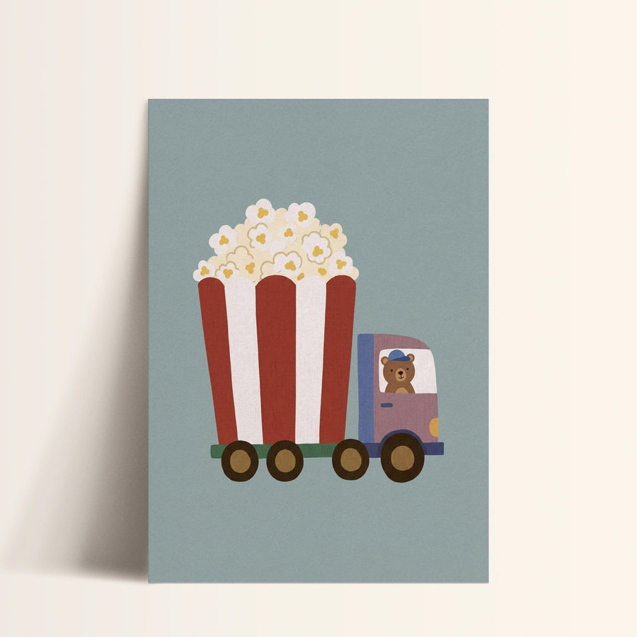 A cartoon image of a red and white striped truck carrying a large bucket of popcorn, with a teddy bear inside the truck.