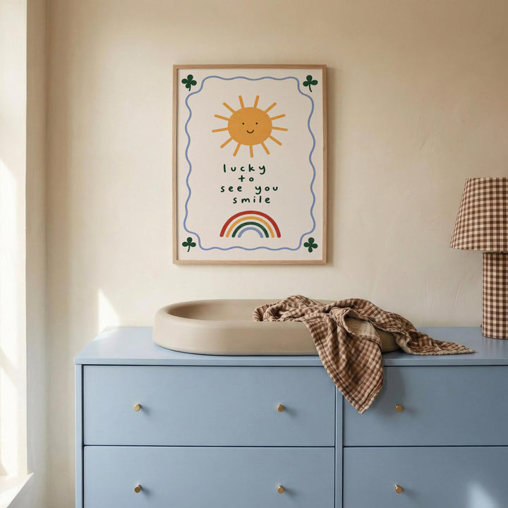 a blue dresser with a white sink on top, and a framed poster with a sun and rainbow design hanging on the wall above the dresser.