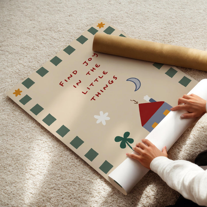 A child's hands are seen rolling up a poster with a message about finding joy in the little things.