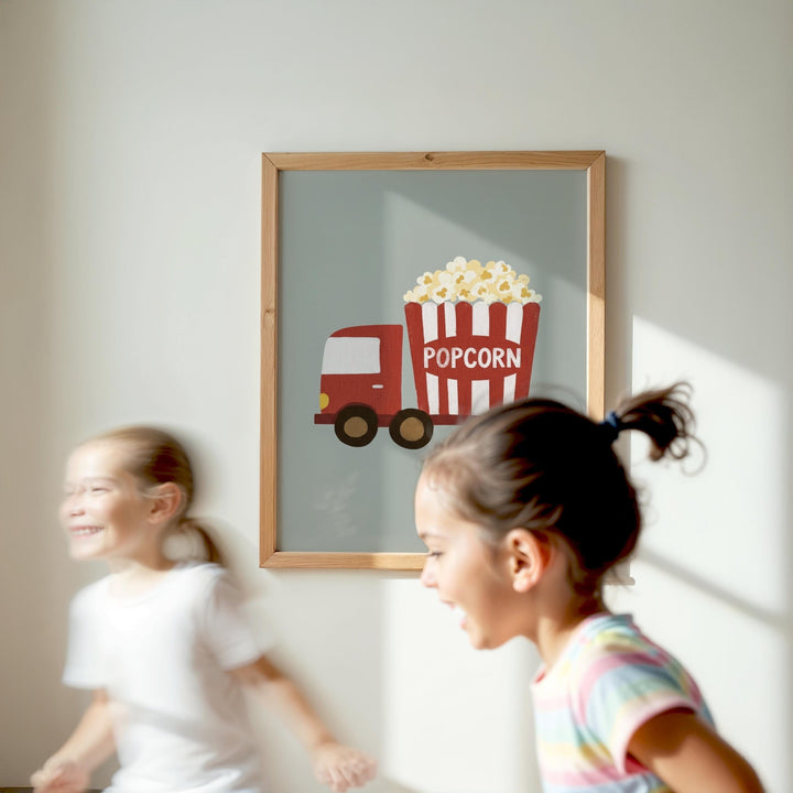 Two young girls are running in front of a framed picture of a red and white popcorn truck.