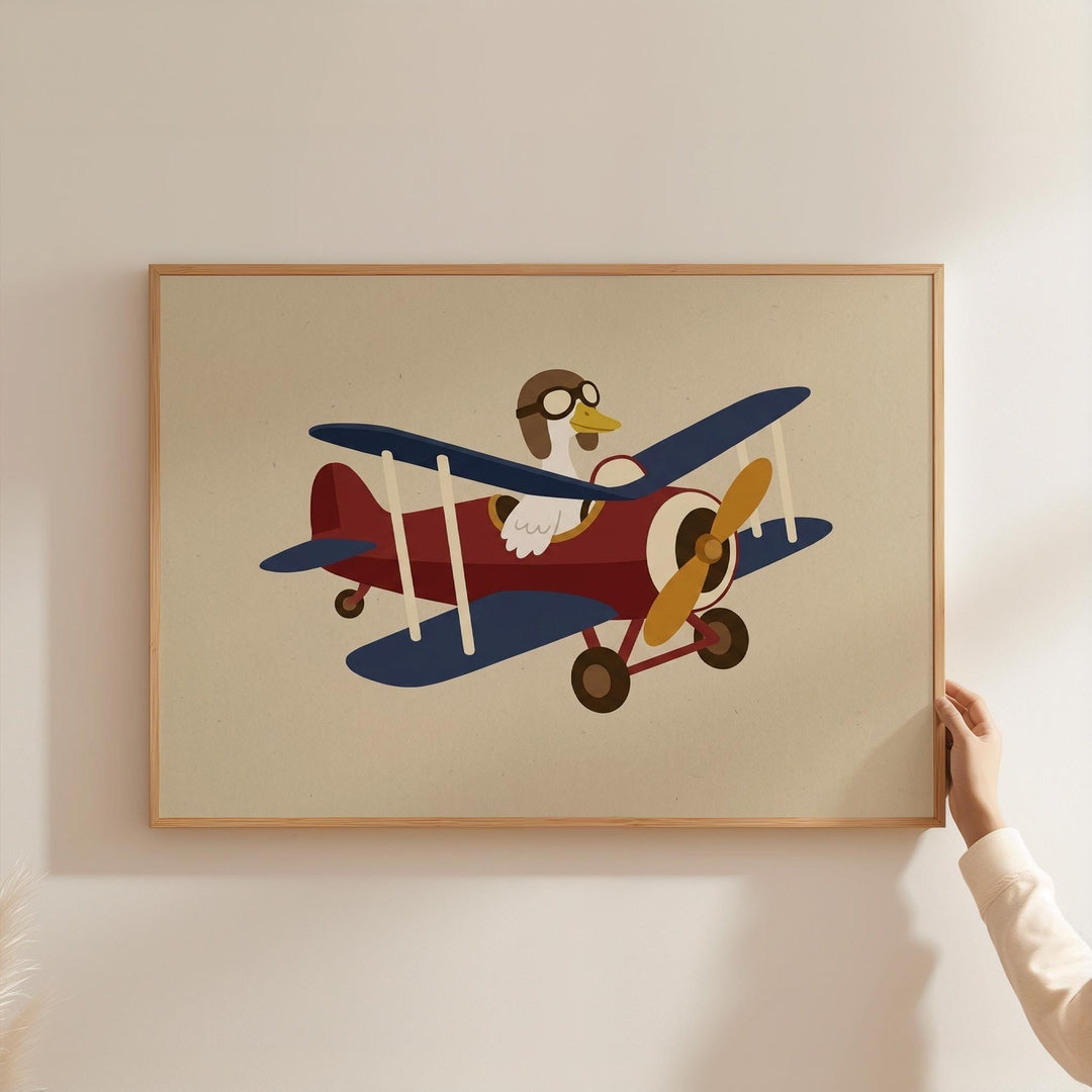 A person is holding a framed picture of a cartoon airplane with a duck piloting it.