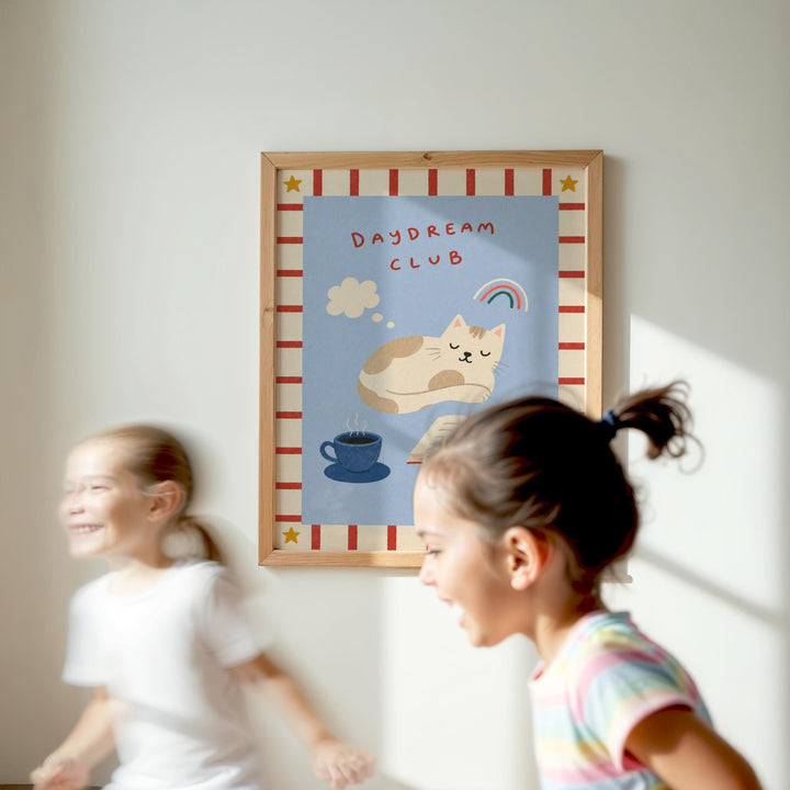 Two young girls are running in front of a framed poster with a cat illustration and the text "Daydream Club" on a white wall.