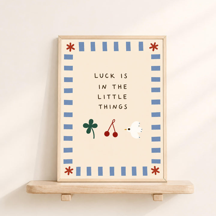 a framed poster with the text "LUCK IS IN THE LITTLE THINGS" and illustrations of a clover, a bird, and a flower.