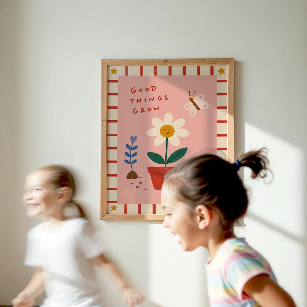 Two young girls are running in front of a framed poster with a flower and butterfly design, which says "Good things grow".