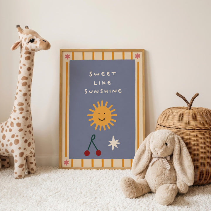 a giraffe, a stuffed rabbit, and a wicker basket, all placed on a white carpet. In the background, there is a framed poster with a sun and a message that reads "Sweet like sunshine".