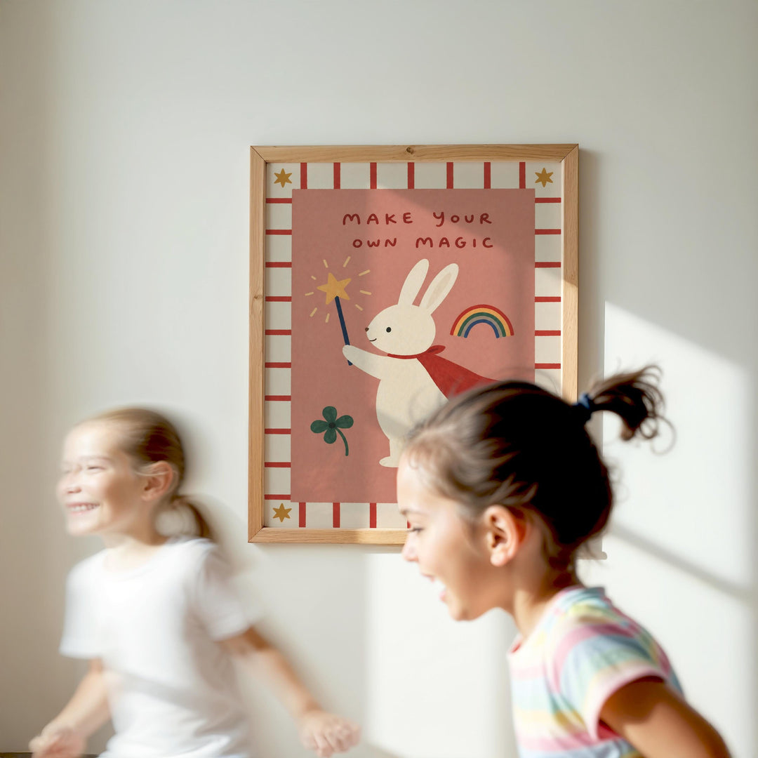 Two young girls are running in front of a framed poster with a rabbit and a rainbow, with the text "MAKE YOUR OWN MAGIC" on the poster.