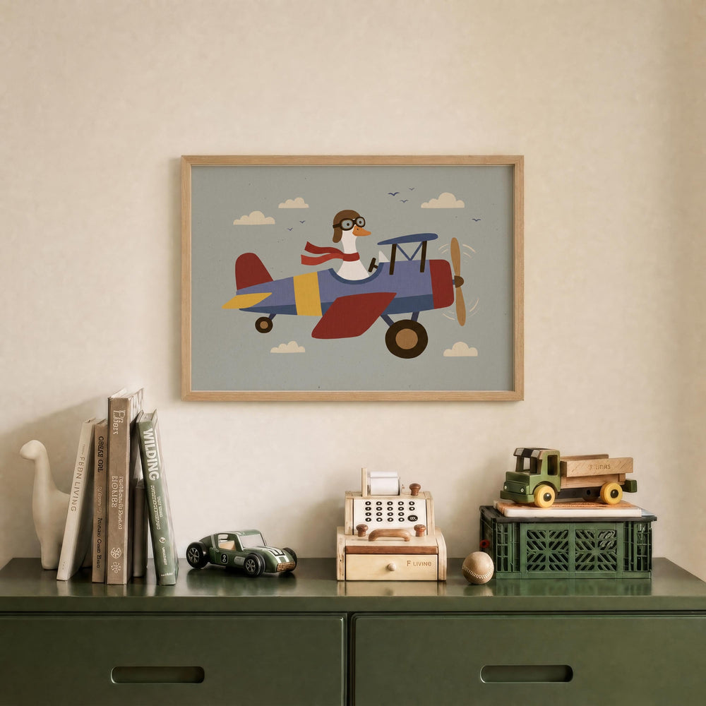 a framed illustration of a duck wearing a pilot's hat and flying a colorful airplane, displayed on a wall above a green dresser with various toys and books.