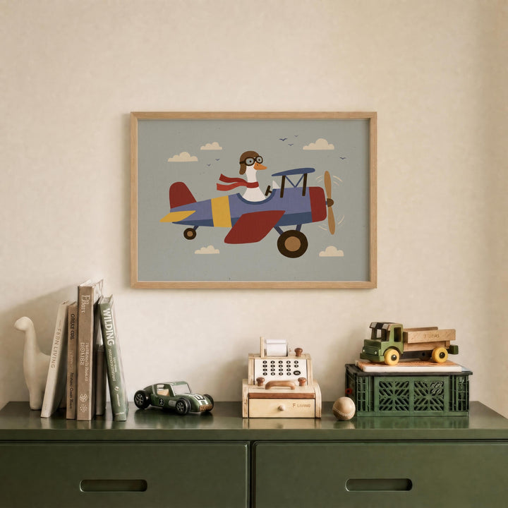 a framed illustration of a duck wearing a pilot's hat and flying a colorful airplane, displayed on a wall above a green dresser with various toys and books.