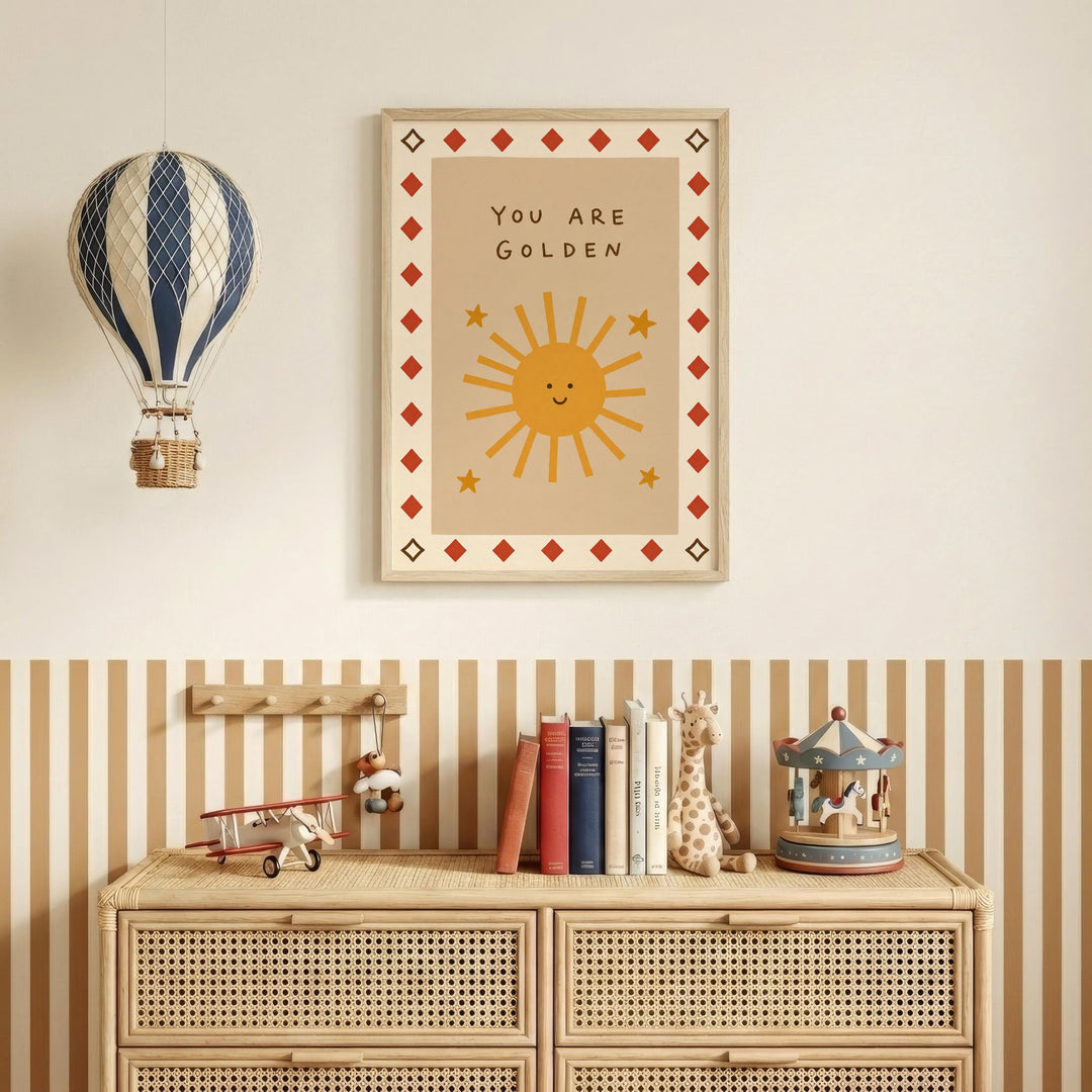 a wall with a framed poster that says "You are Golden" above a wooden dresser with a toy airplane and a carousel.